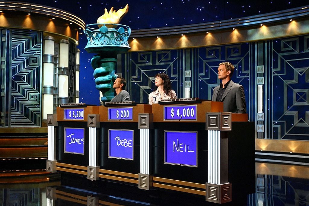 James Denton, Bebe Neuwirth, and Neil Patrick Harris stand at their podiums rehearsing for Celebrity 'Jeopardy!' in 2006