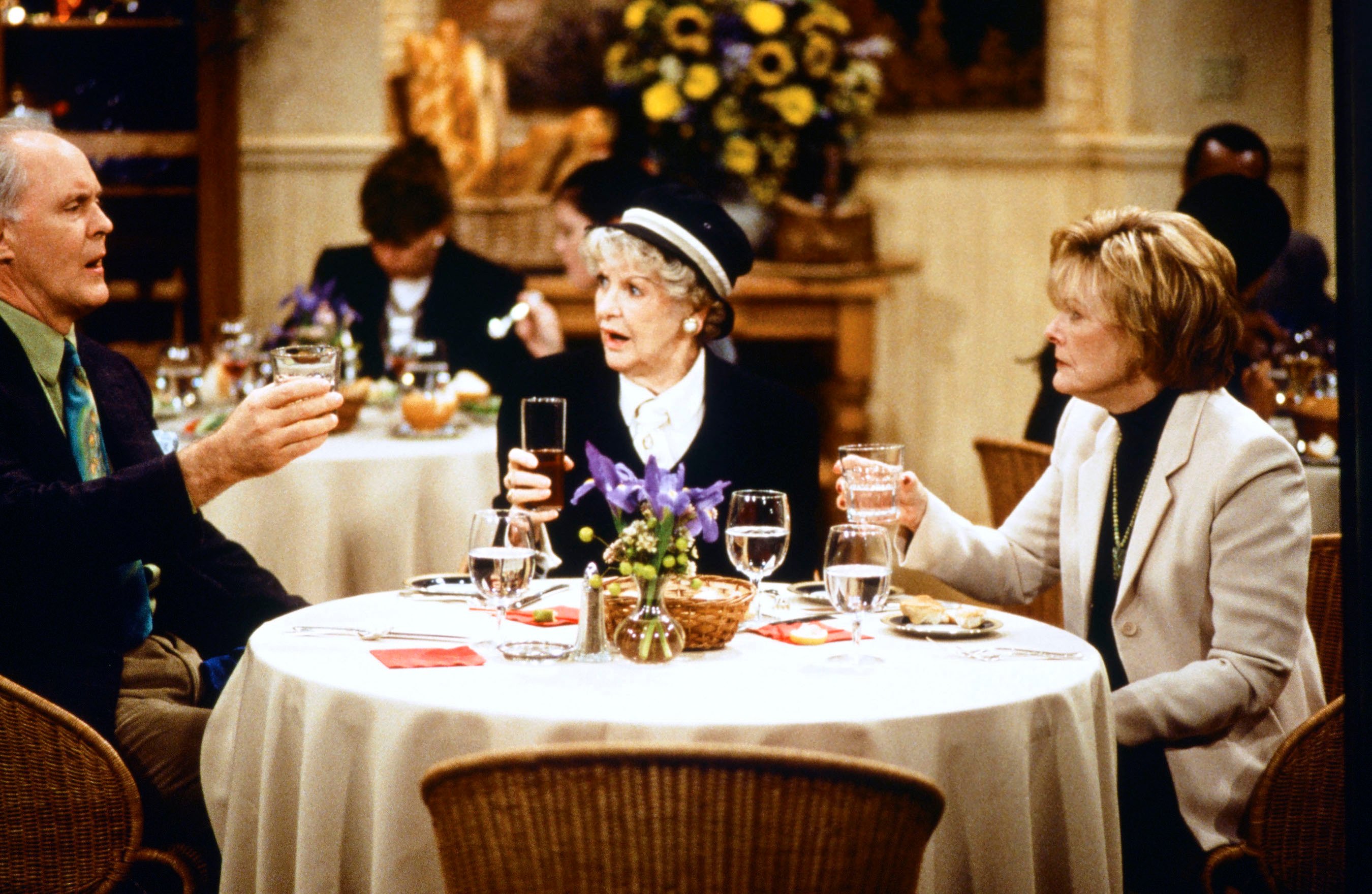 John Lithgow, Elaine Stritch, and Jane Curtin sitting at a table in a scene from '3rd Rock from the Sun'