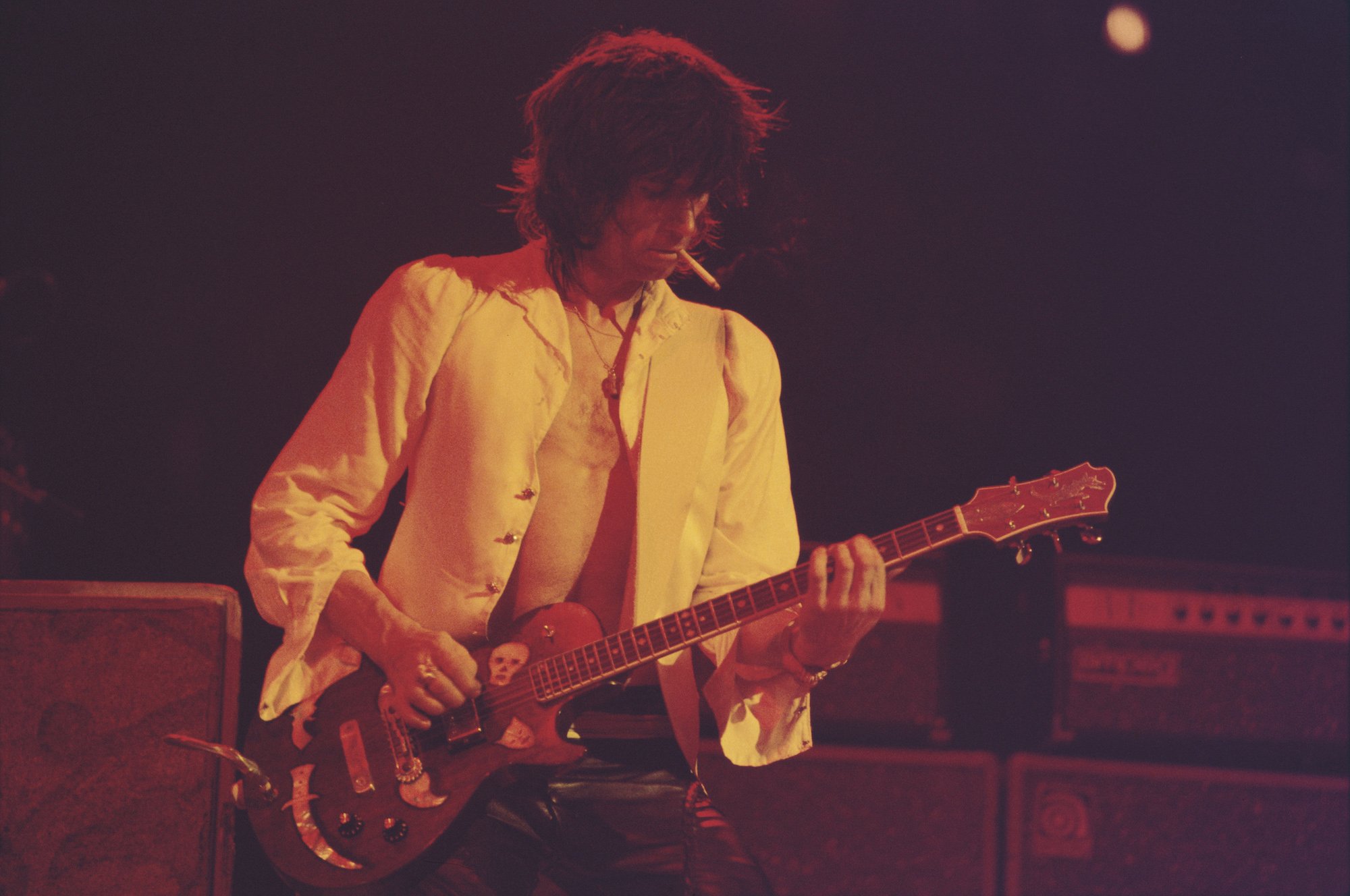 Keith Richards smoking on stage while playing guitar, looking down