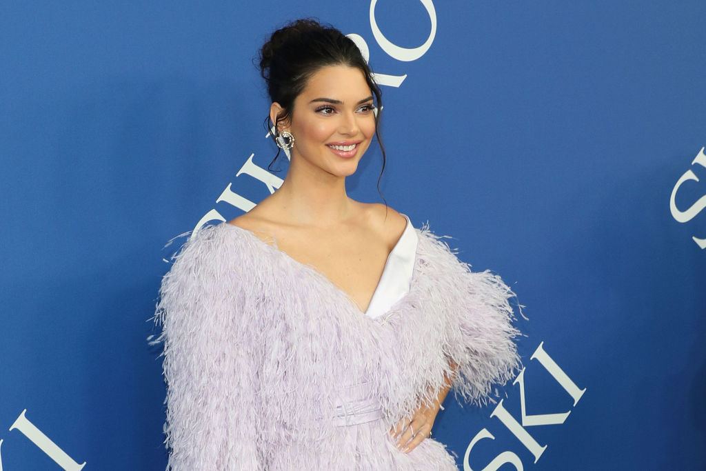 Kendall Jenner smiling in front of a blue background