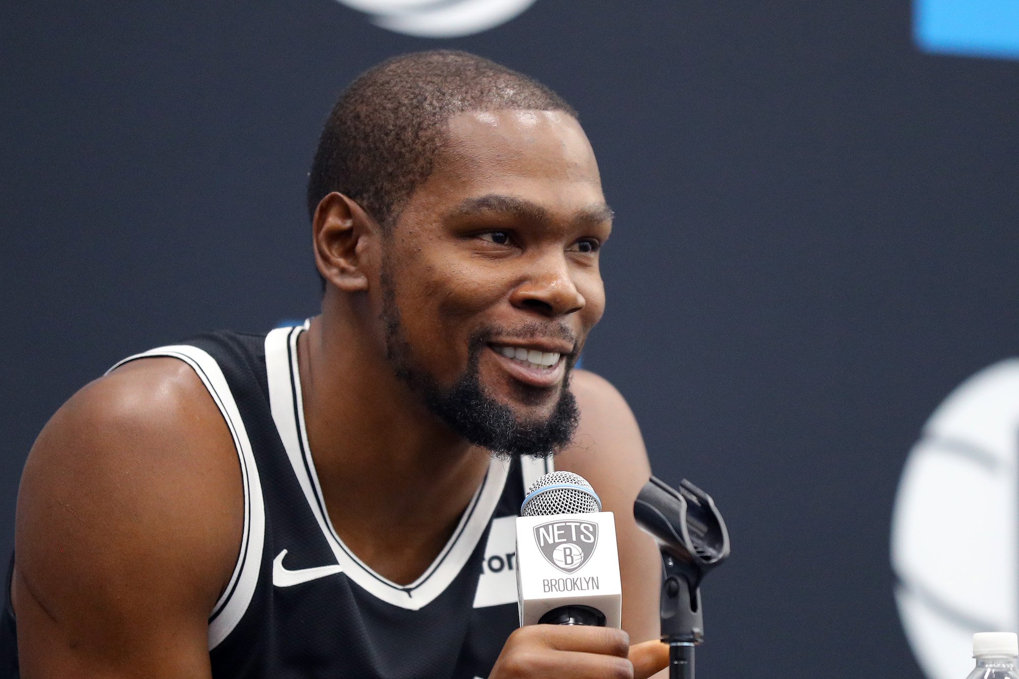 Kevin Durant smiling, holding a microphone