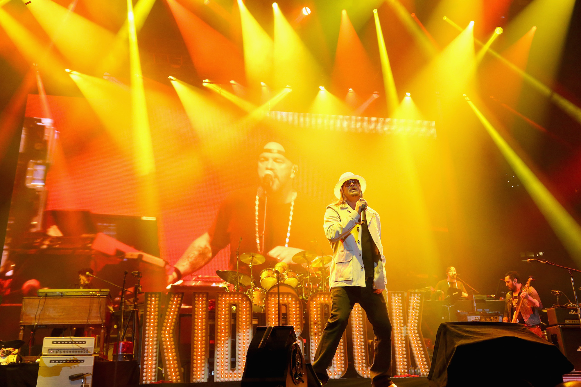 Kid Rock on stage under yellow and orange lighting