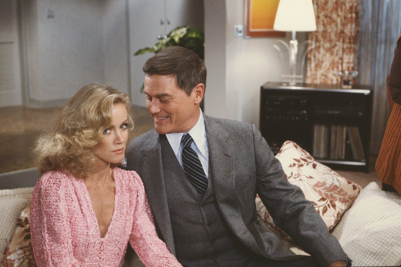 Donna Mills (as Abby Cunningham) looking at the camera, not smiling and Larry Hagman (as J.R. Ewing) smiling at Mills