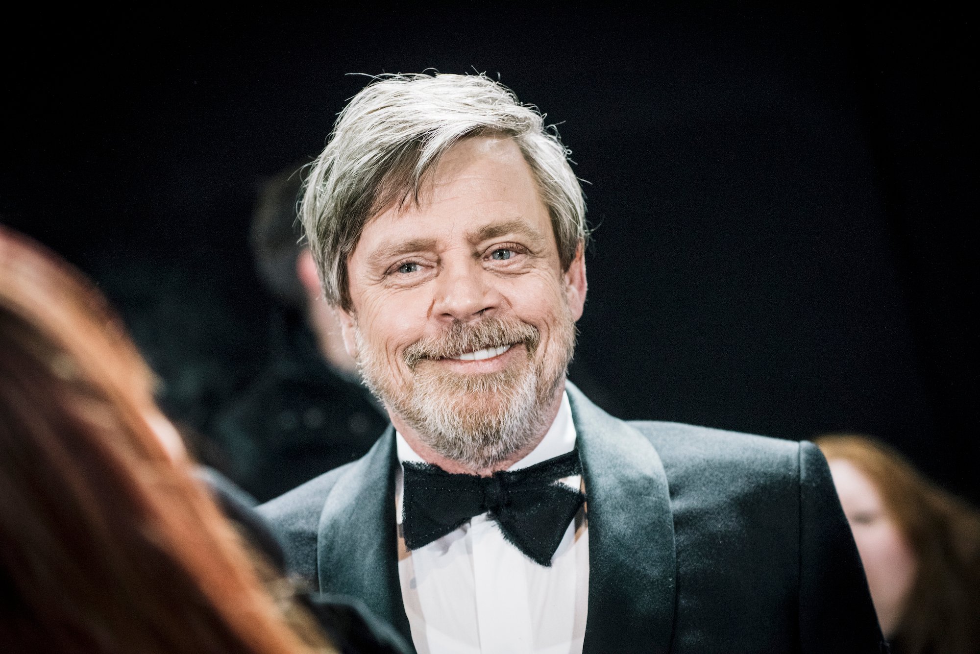 Mark Hamill smiling, wearing a suit and bowtie
