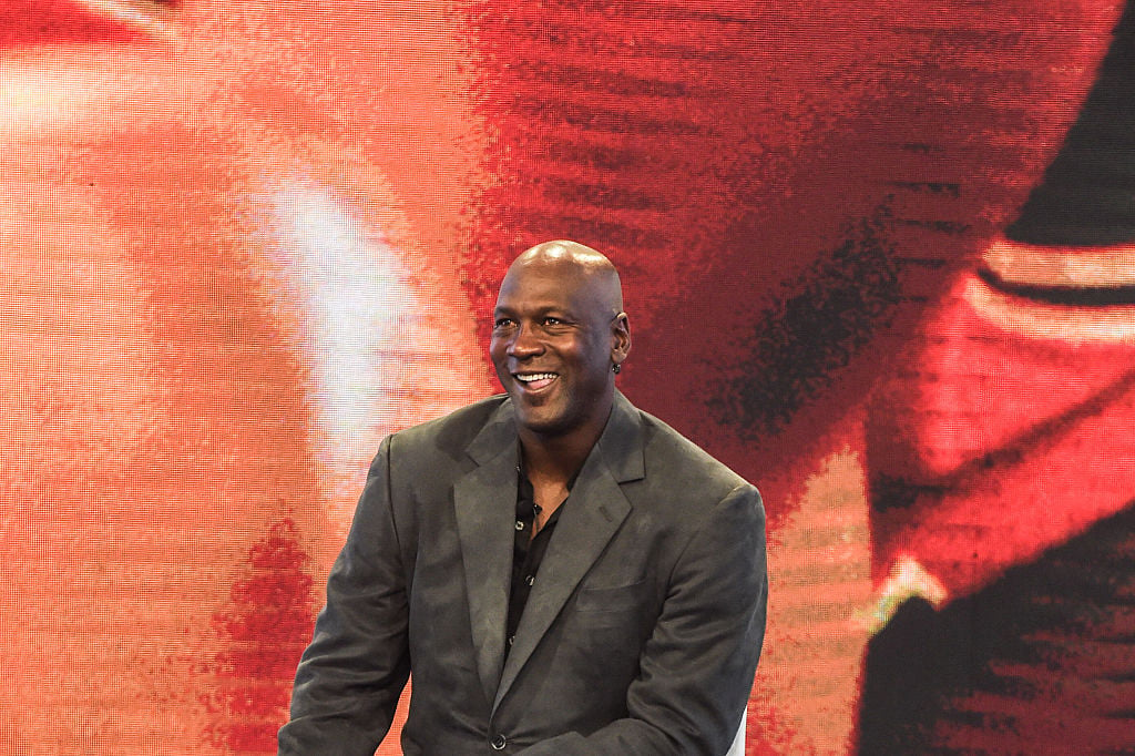 Michael Jordan smiling in front of a red background