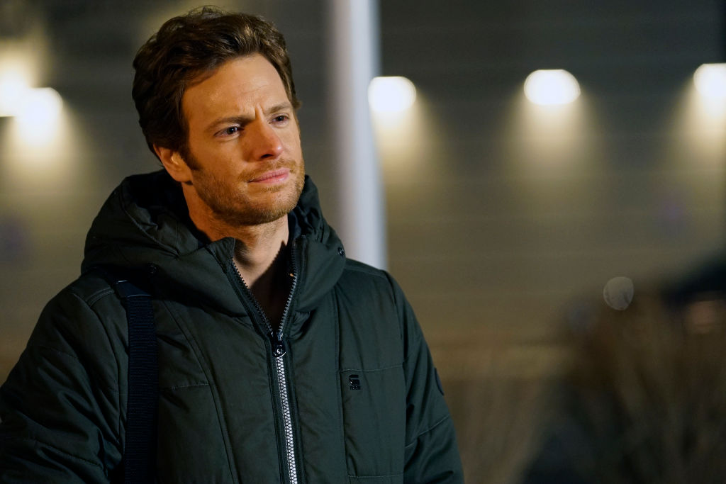 Nick Gehlfuss as Will Halstead smiling, wearing a winter jacket on set of 'Chicago Med'