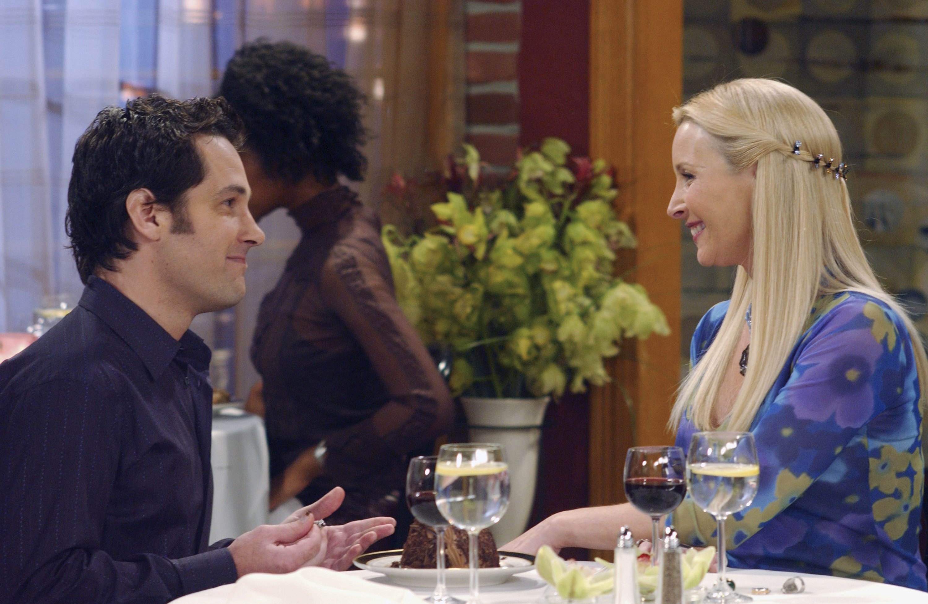 Paul Rudd as Mike Hannigan sitting at a table across from Lisa Kudrow as Phoebe Buffay in 'Friends'