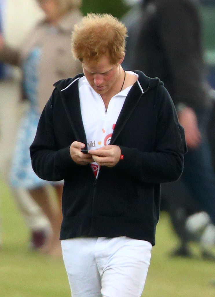 Prince Harry looks at his phone during the 2015 Audi Polo Challenge