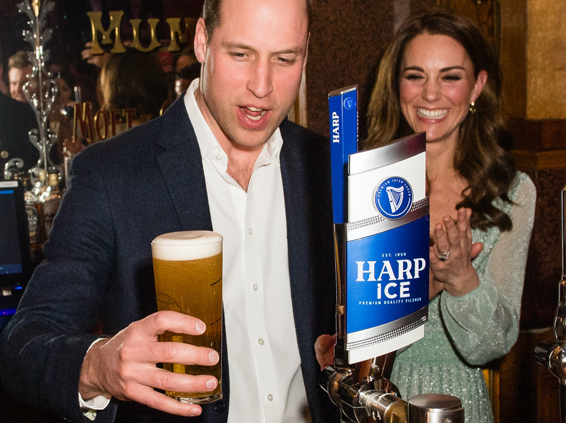 Prince William pours a pint of beer while Kate Middleton watches