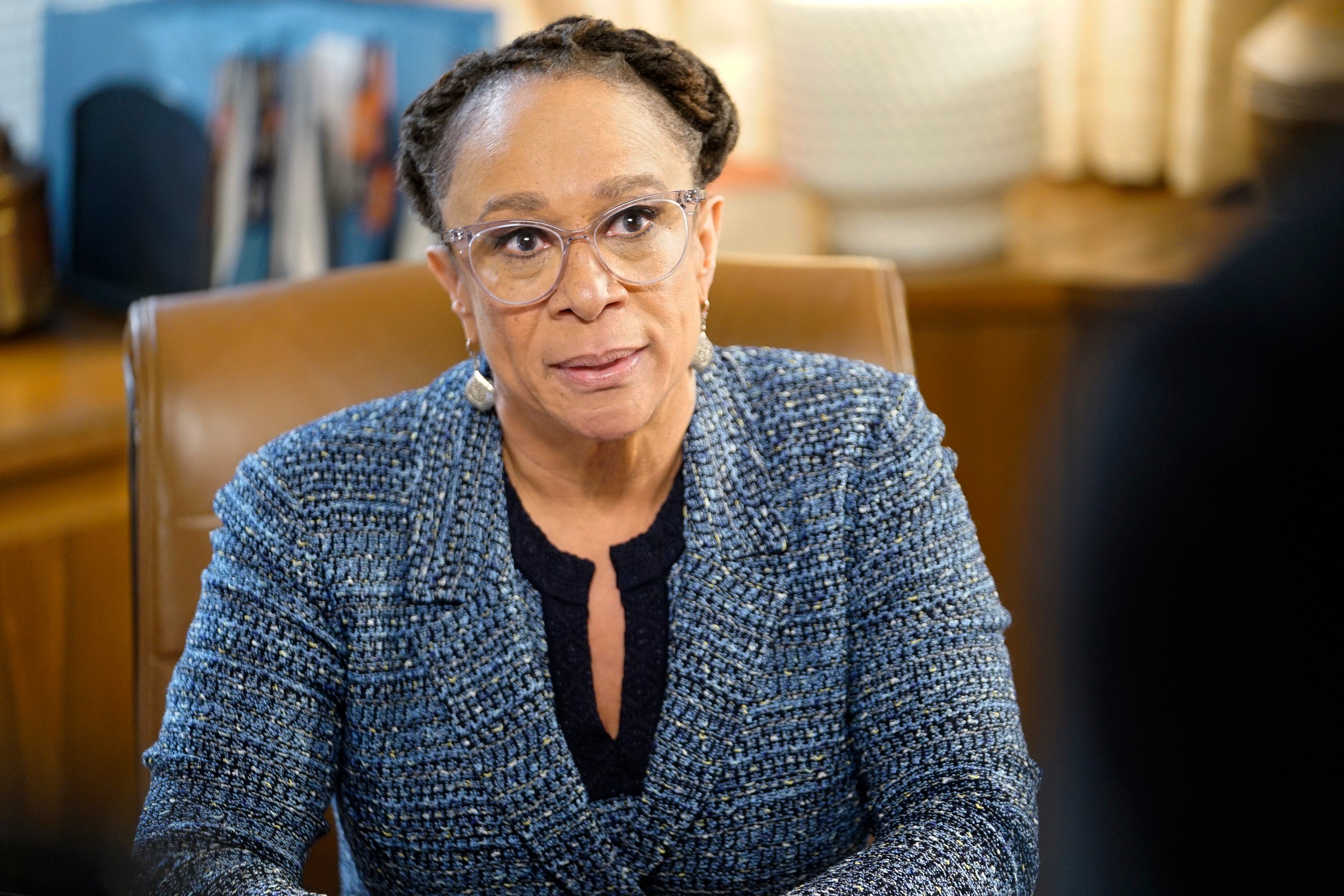 S. Epatha Merkerson as Sharon Goodwin on 'Chicago Med' sitting at a desk, wearing glasses, looking up and away from the camera