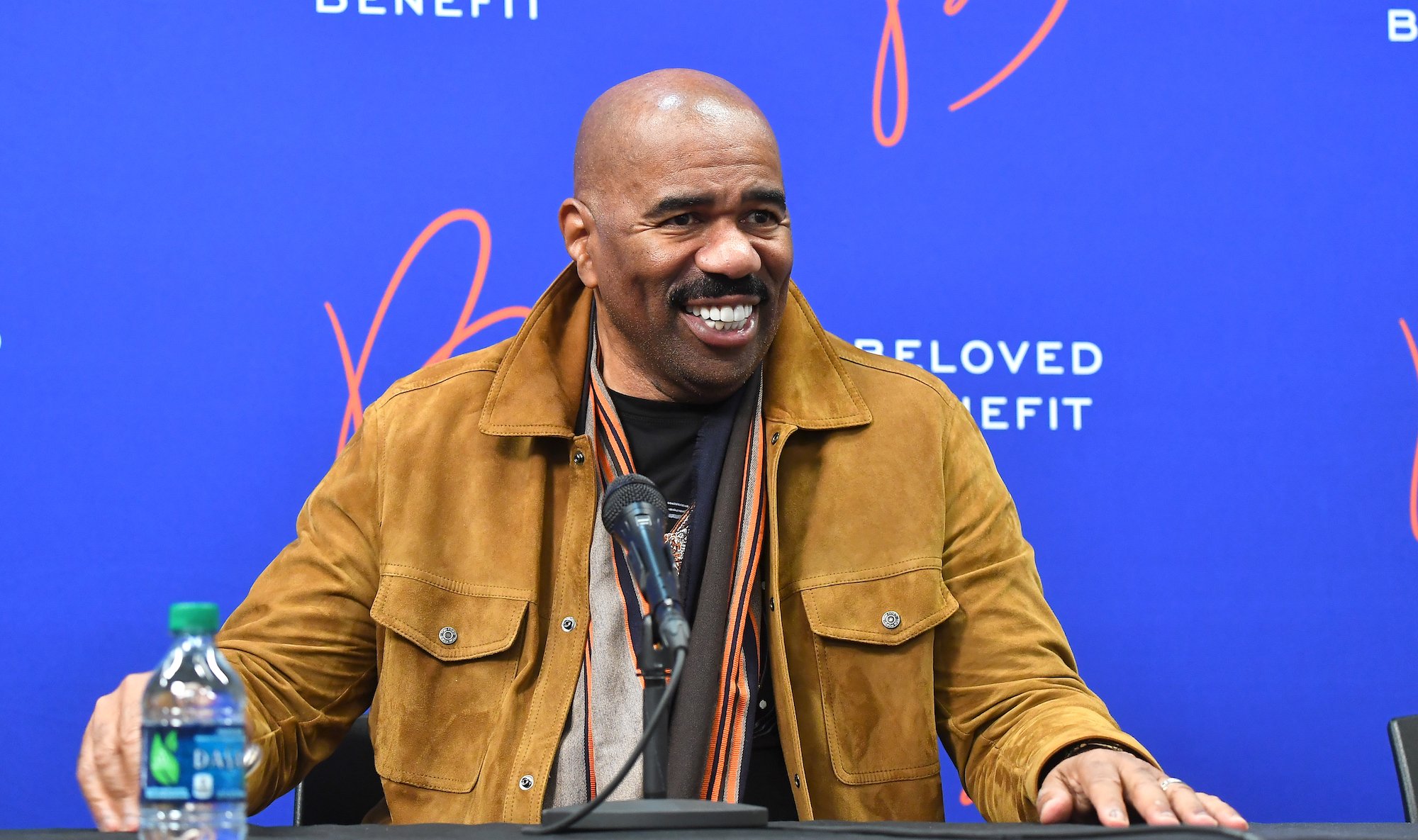 Steve Harvey smiling in front of a blue background
