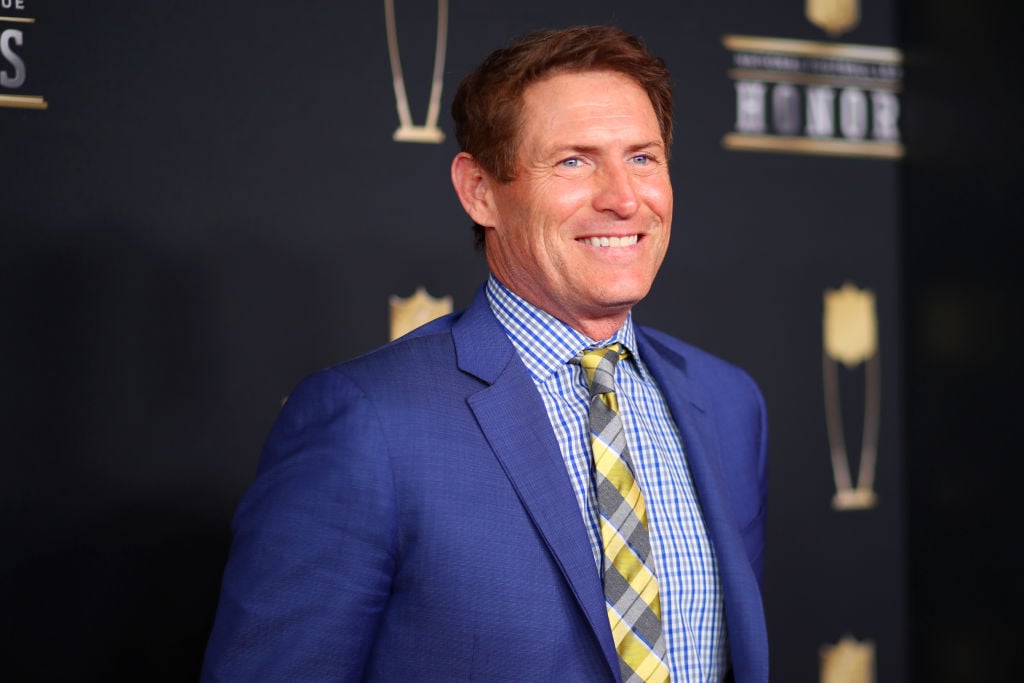 Steve Young smiling in front of a repeating background