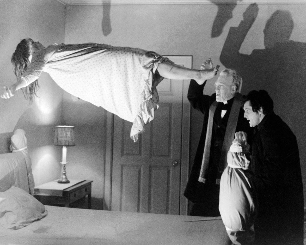 Linda Blair as Regan MacNeil floating in the air, Max von Sydow as Father Merrin, and Jason Miller as Father Karras