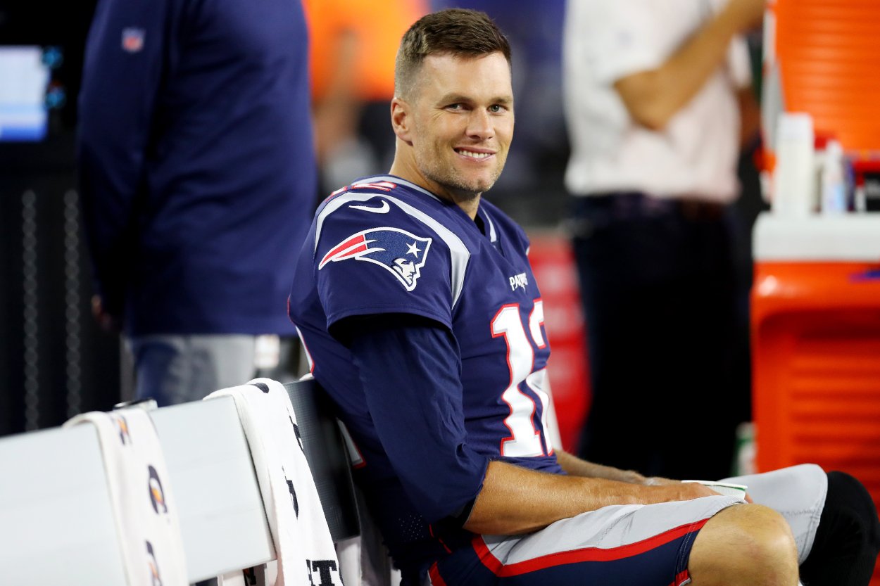 Tom Brady sitting on the bench during a Patriots game smirking