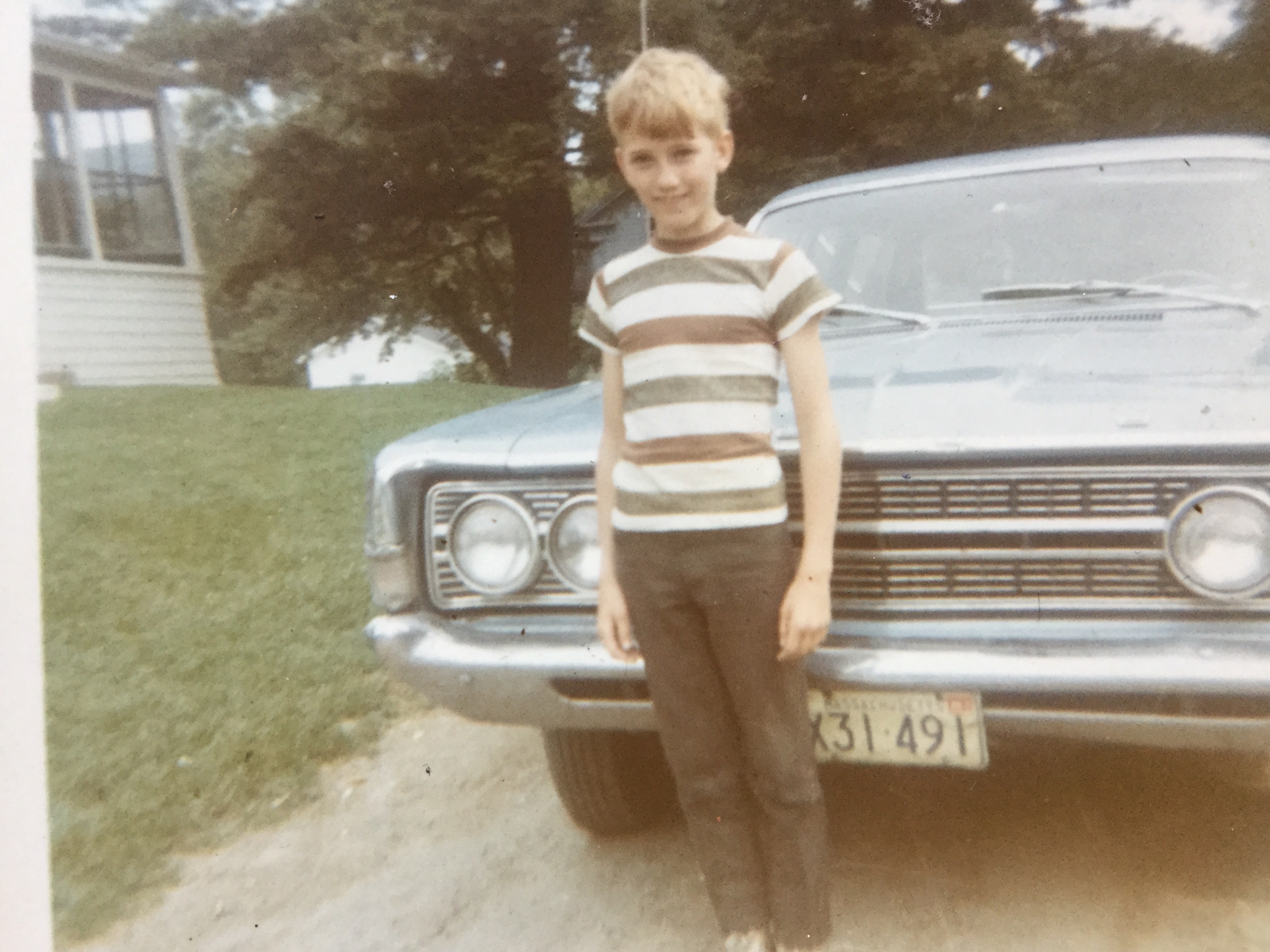 boy standing in front of car
