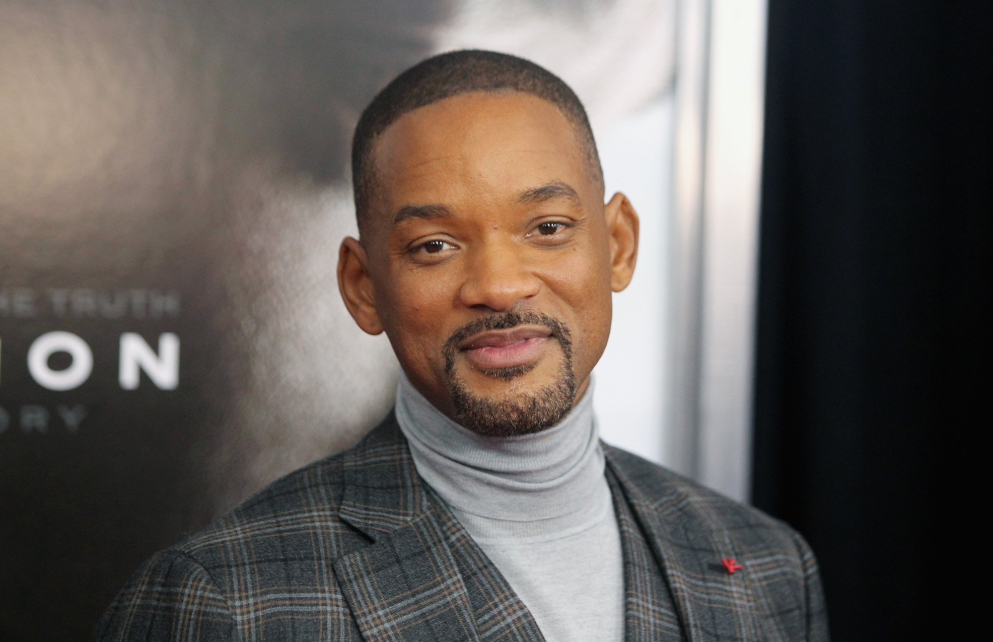 Will Smith smiling at the camera in front of a black background