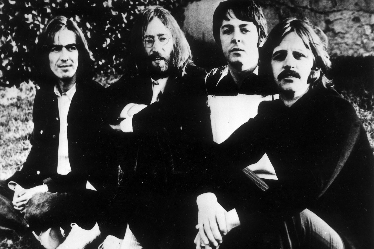 The Beatles seated in a field