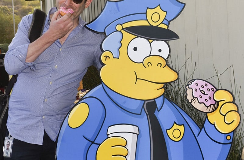 'Simpsons' character Chief Wiggum stands with a donut