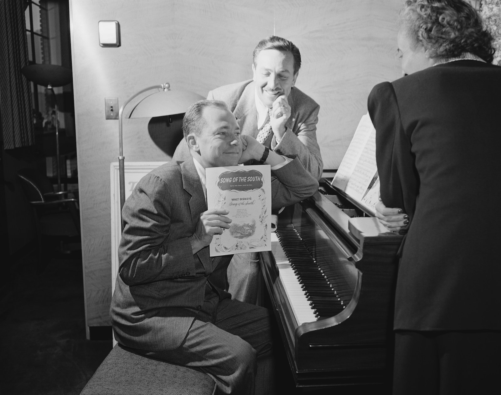 Walt Disney watched musician Johnny Mercer at the piano, as he holds up the sheet music from Disney's 'Song of the South' movie, October 28, 1946.