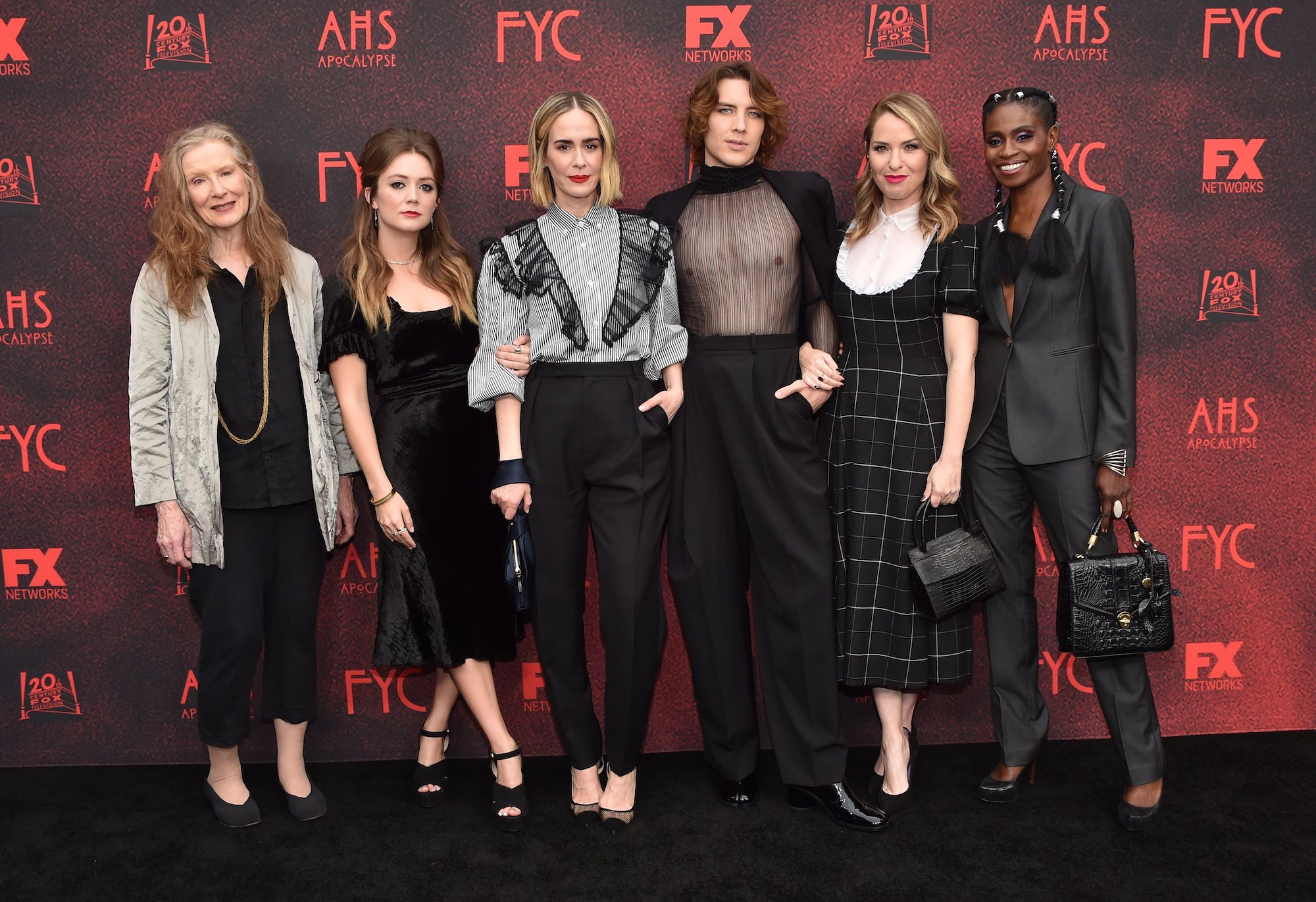 (From L-R) Actors Frances Conroy, Billie Lourd, Sarah Paulson, Cody Fern, Leslie Grossman and Adina Porter in front of a background with a repeating 'American Horror Story' logo
