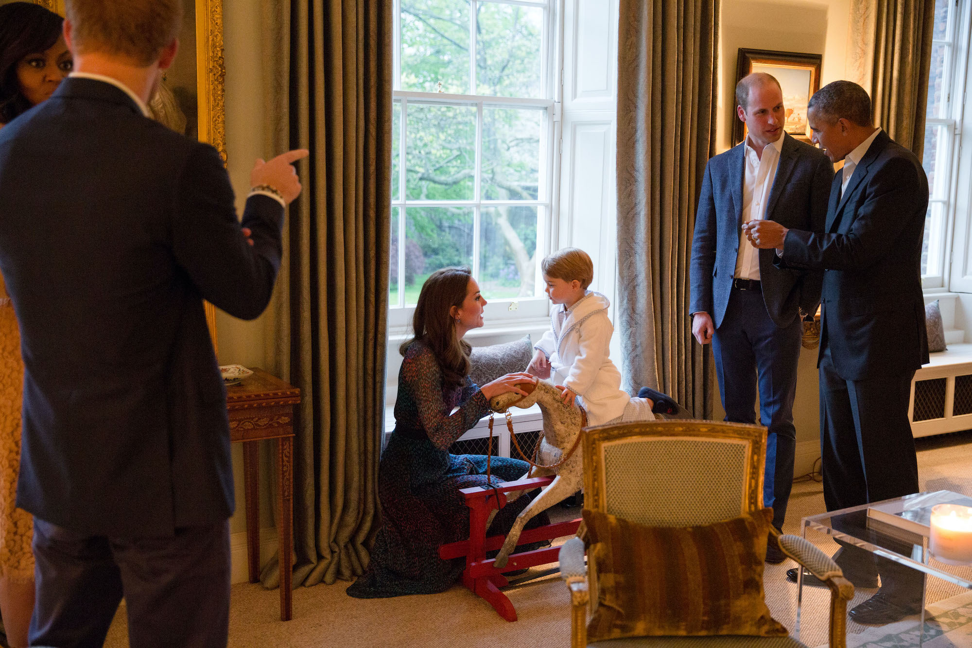 Barack Obama talks with Prince William as Kate Middleton plays with Prince George as Michelle Obama talks with Prince Harry