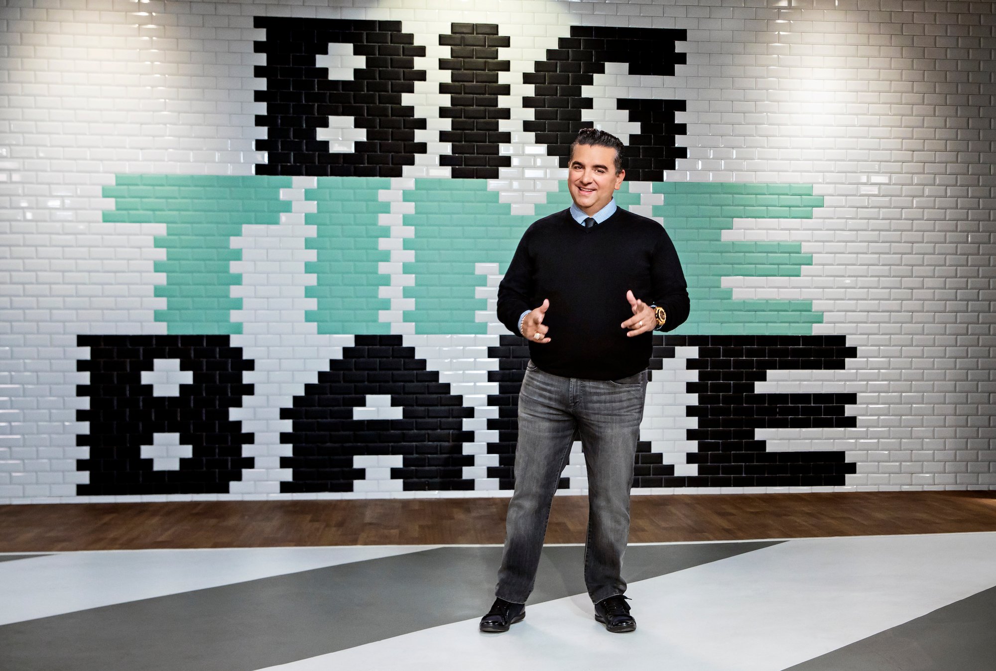 Buddy Valastro in front of a tile wall with the 'Big Time Bake' logo