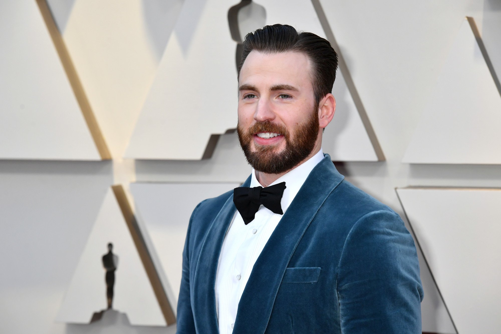 Chris Evans smiling in front of a textured background