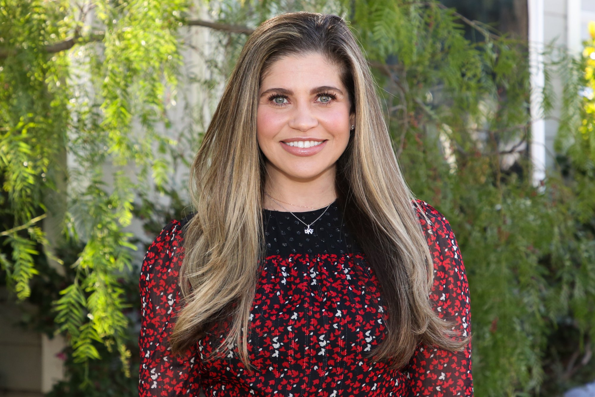Danielle Fishel smiling looking at the camera in front of a tree