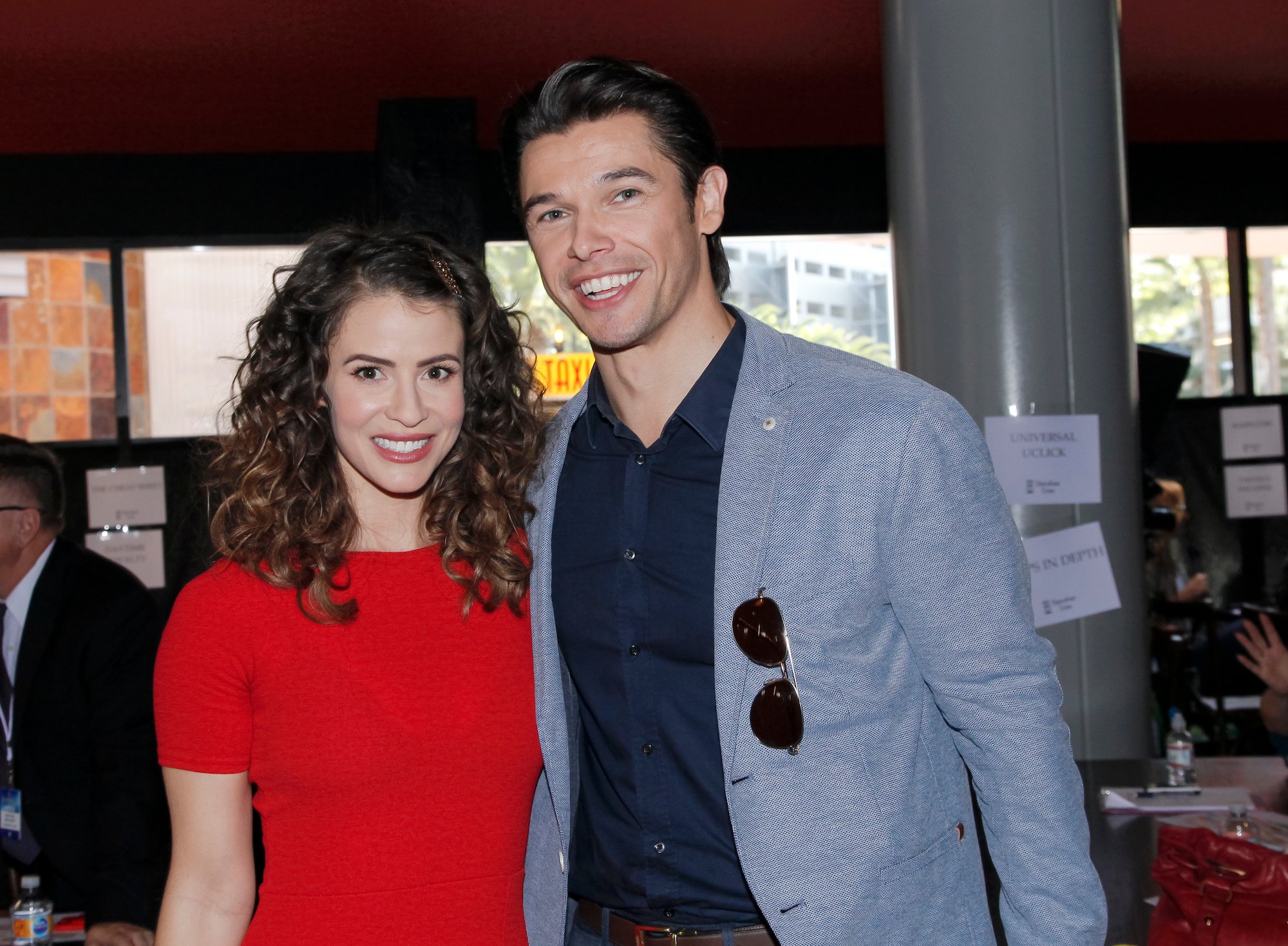 Linsey Godfrey and Paul Telfer smiling, looking at the camera