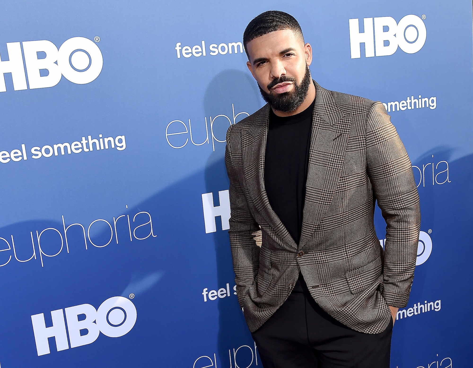 Drake smiling in front of a blue background