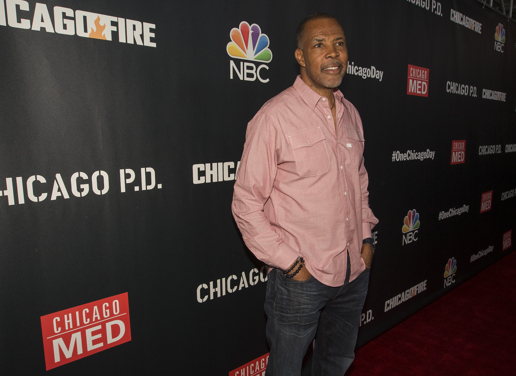 Eriq La Salle smiling, turned into the side, in front of a dark background with repeating 'Chicago' logos