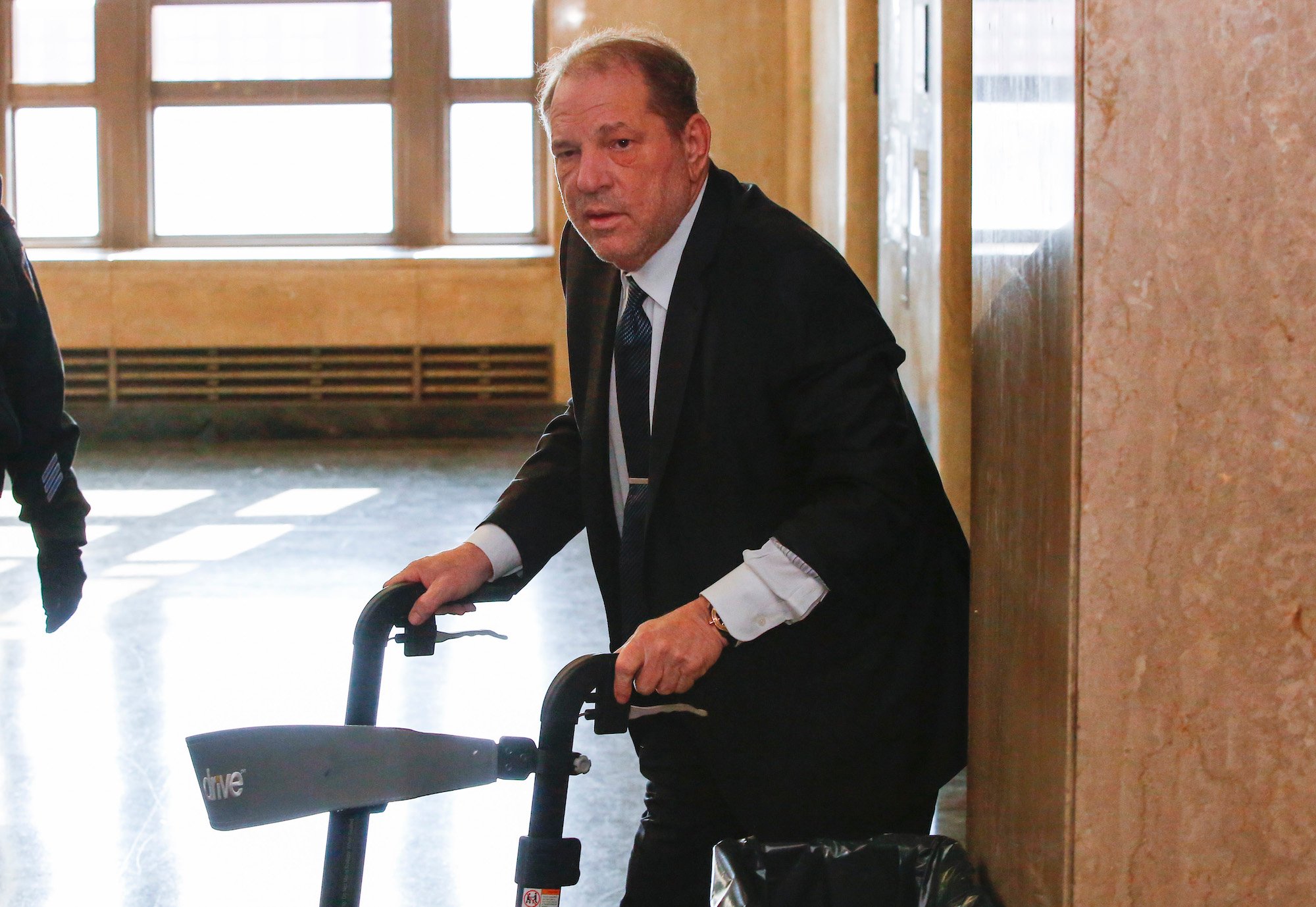 Harvey Weinstein hunched over a walker