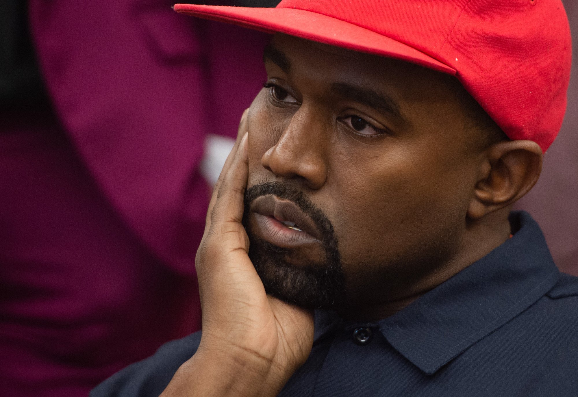 Kanye West resting his face on his hand, looking off camera