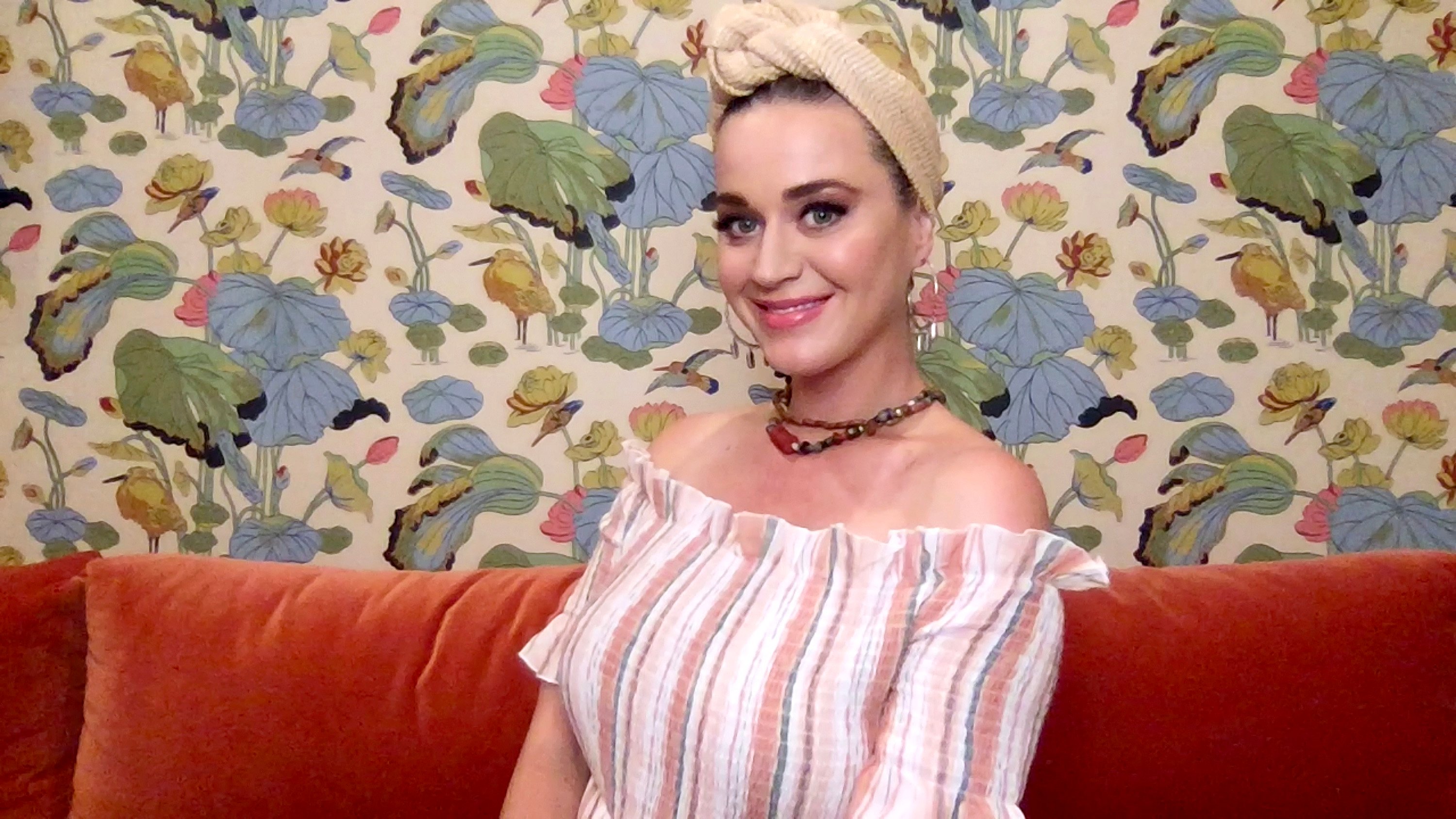 Katy Perry with her hair up, in front of a floral background