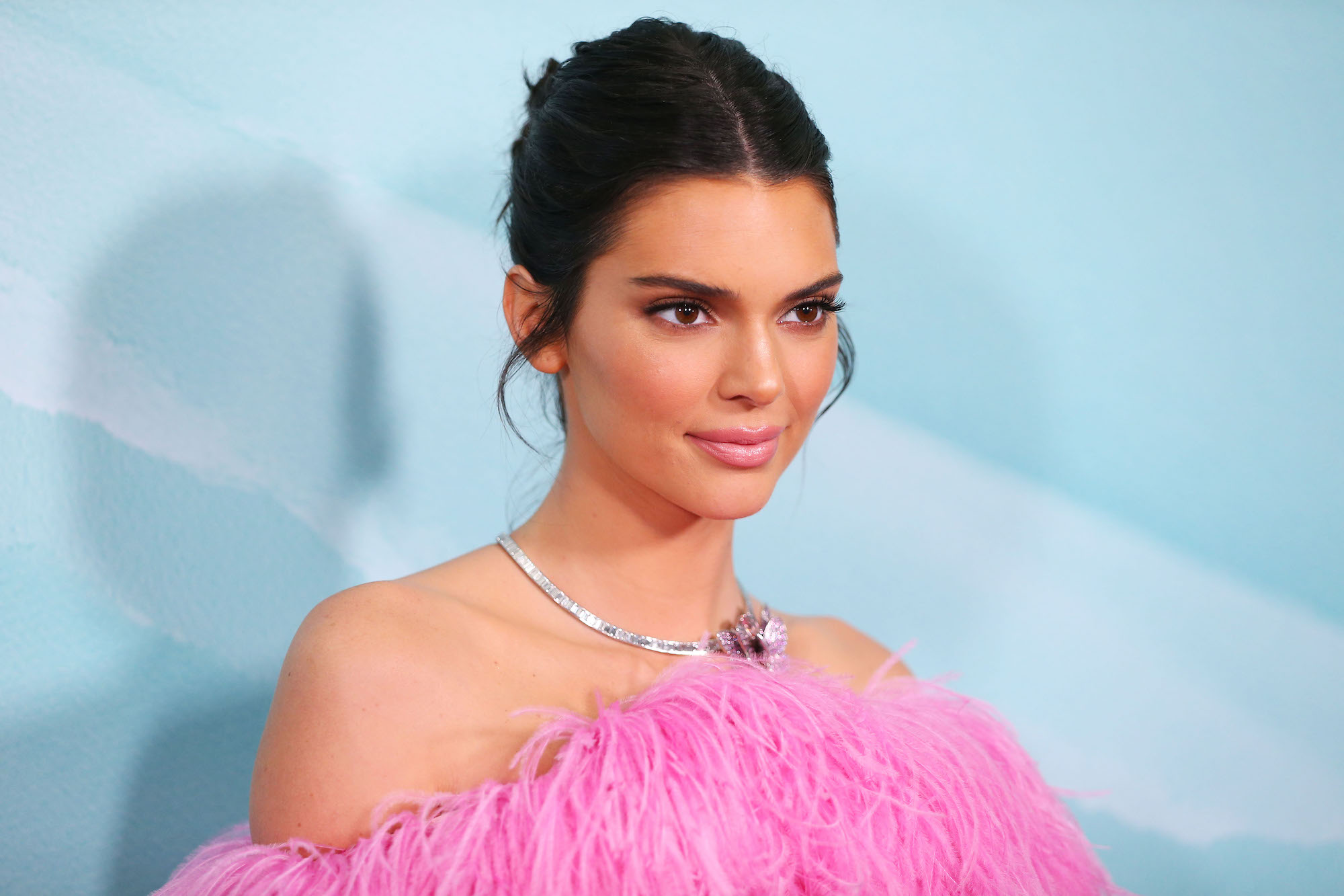Kendall Jenner smiling in front of a blue background