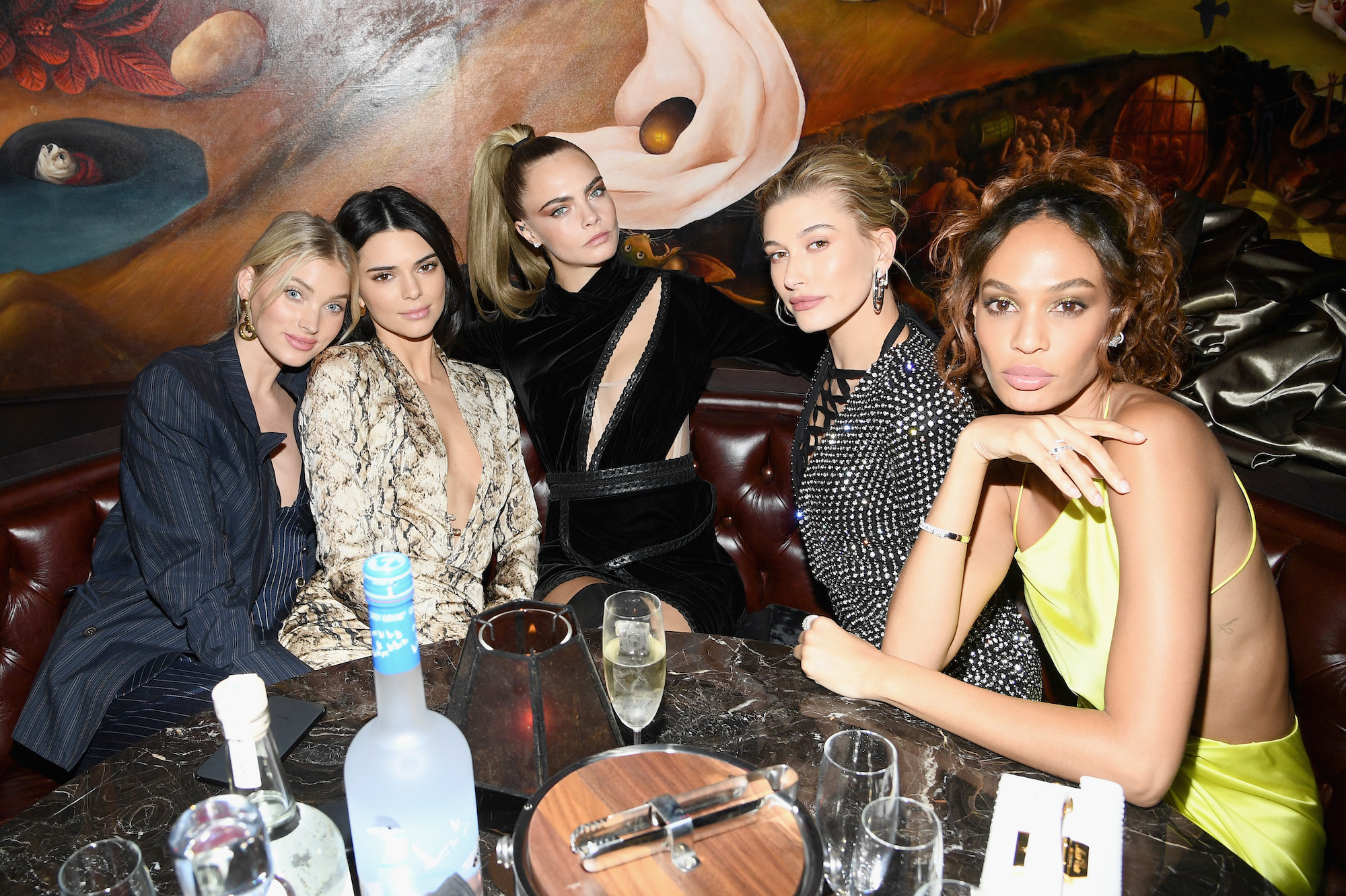 (L-R) Elsa Hosk, Kendall Jenner, Cara Delevingne, Hailey Bieber, and Joan Smalls sitting in a booth at a restaurant