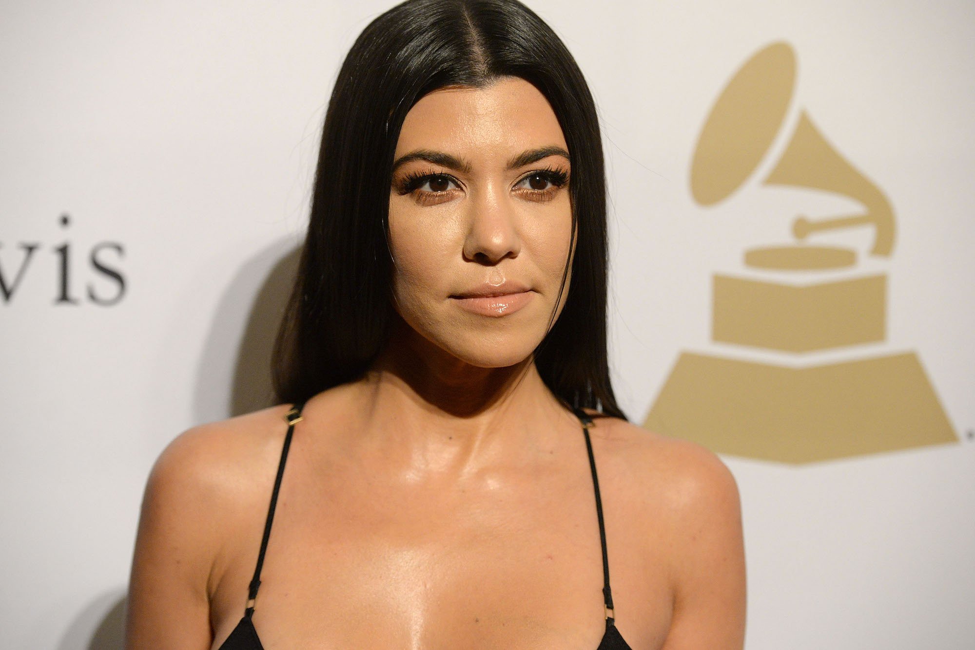 Kourtney Kardashian smiling slightly in front of a light background