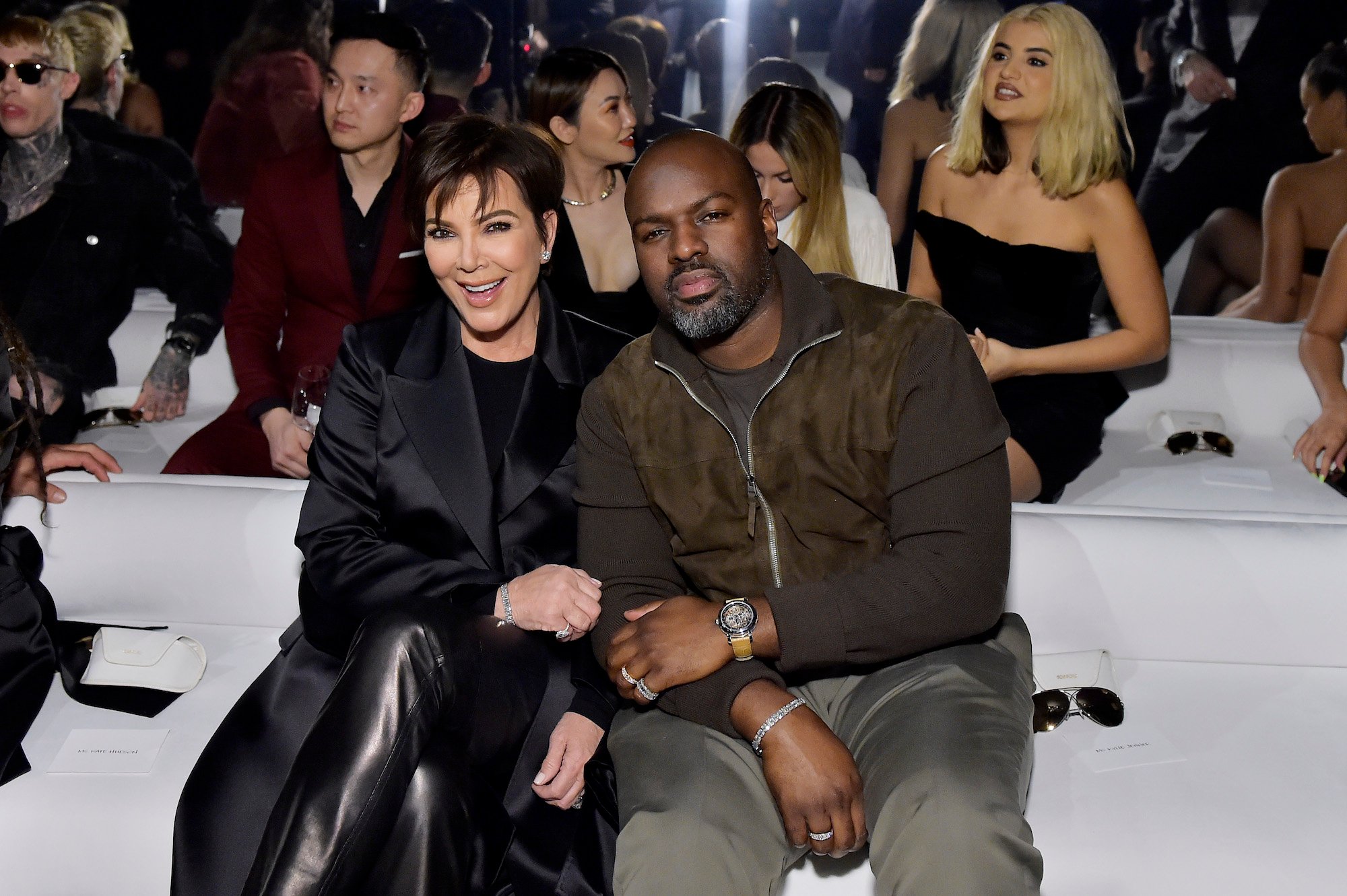 Kris Jenner and Corey Gamble smiling in the front row of a fashion show