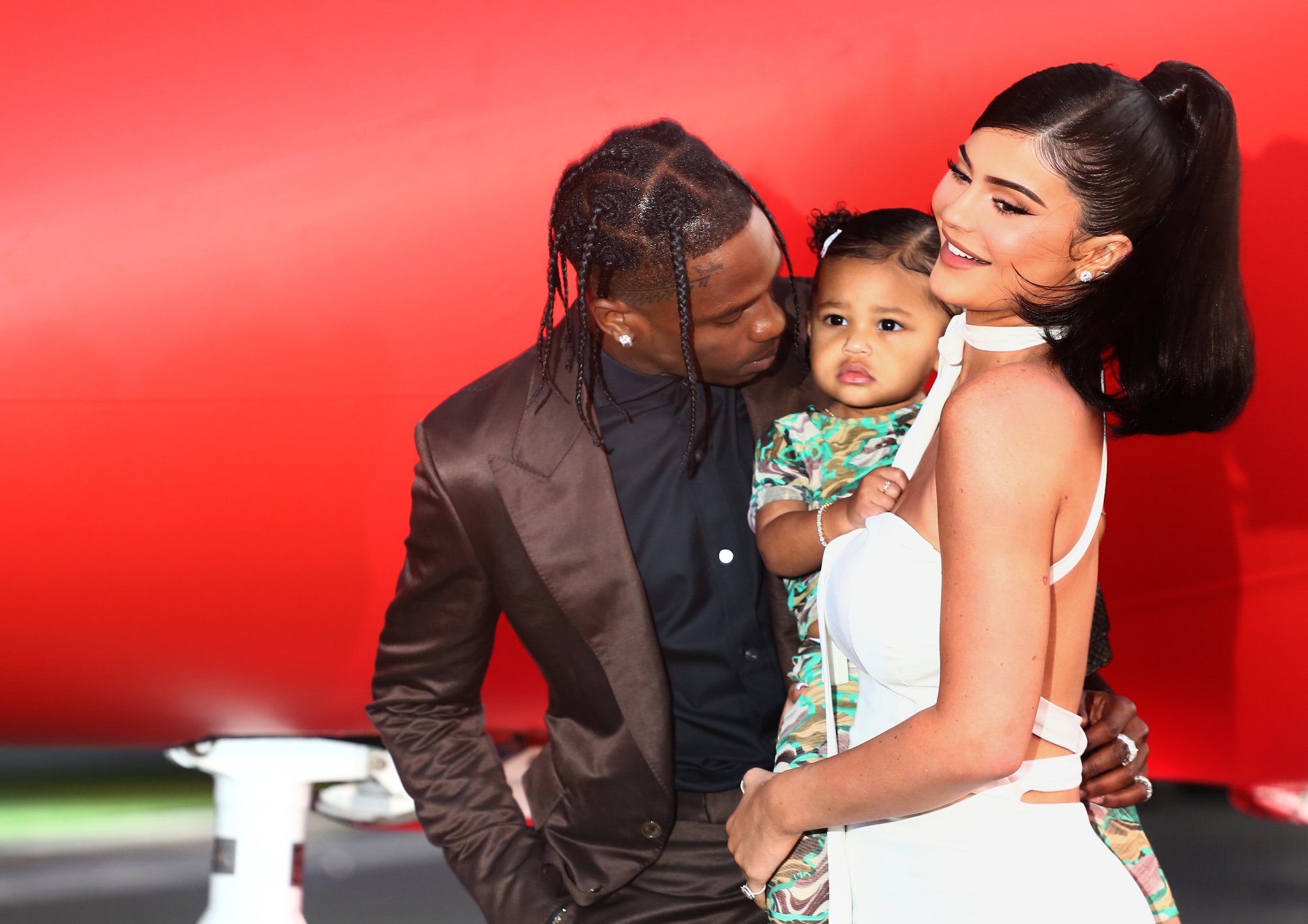 Travis Scott looking at Stormi Webster, held by Kylie Jenner