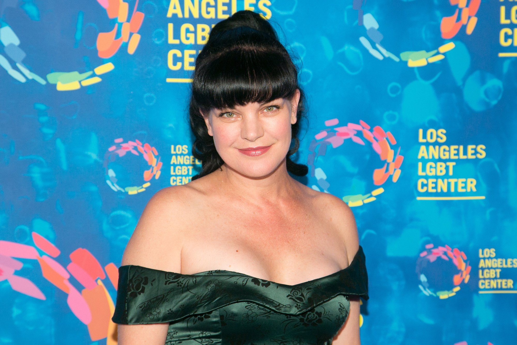 Pauley Perrette smiling in front of a blue background