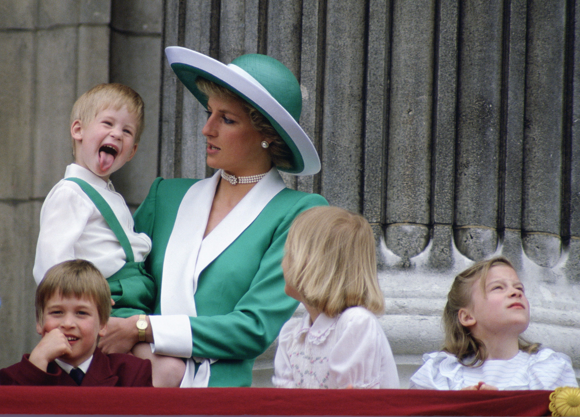 Prince Harry as a young child, sticking out his tongue, while Princess Diana is holding him