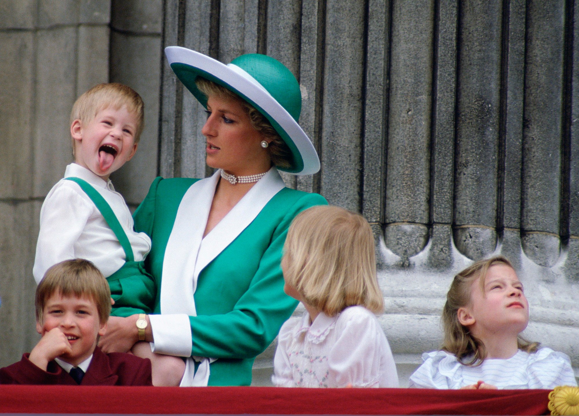 Prince Harry as a young child, sticking out his tongue, while Princess Diana is holding him