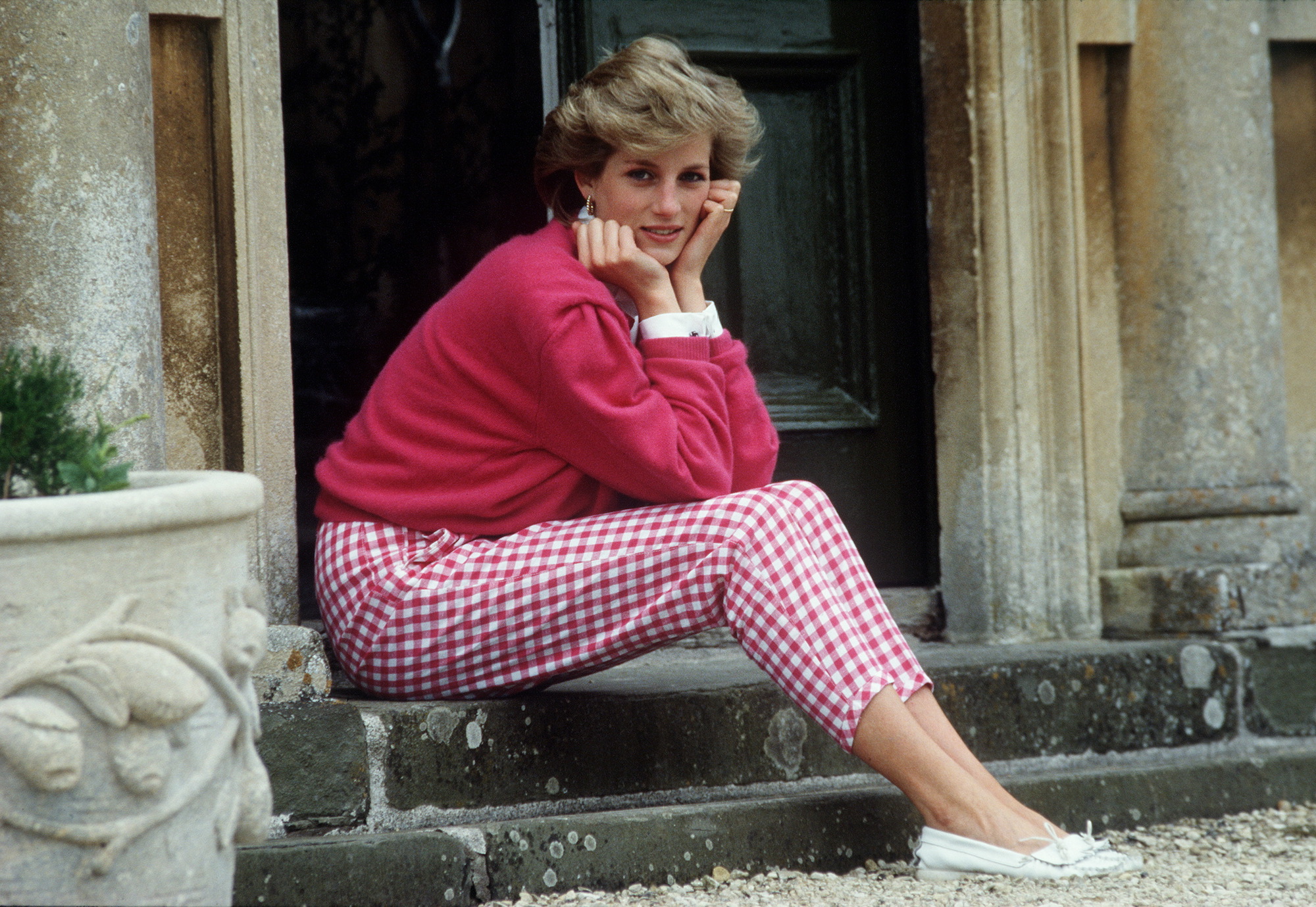 Princess Diana smiling in a pink sweater and pink and white checkered pants