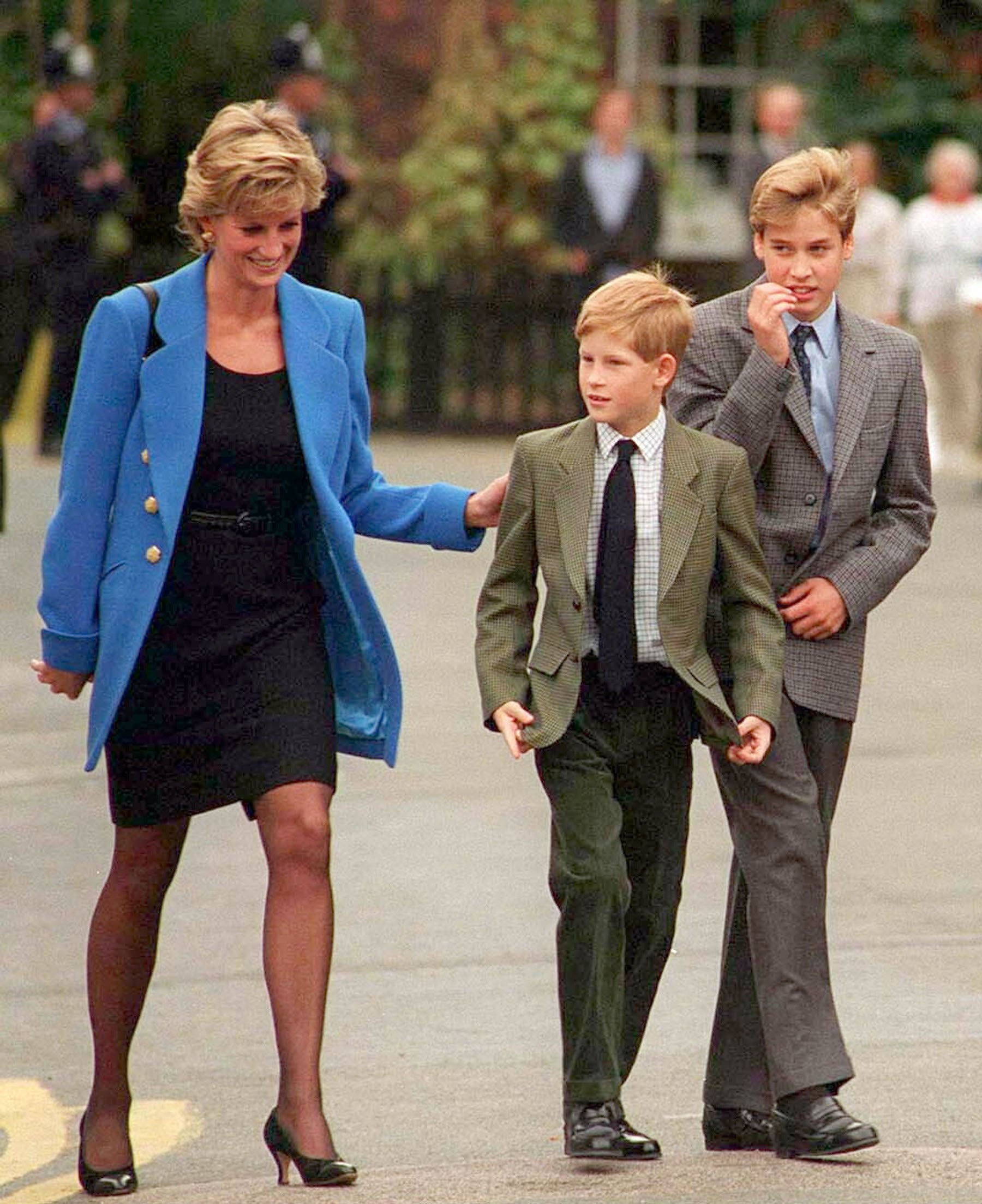 Princess Diana puts her arm on Prince Harry's shoulder while Prince William walks next to Prince Harry