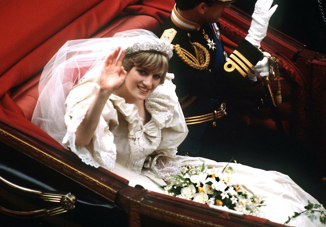 Princess Diana and Prince Charles wave while riding in a carriage during their royal wedding
