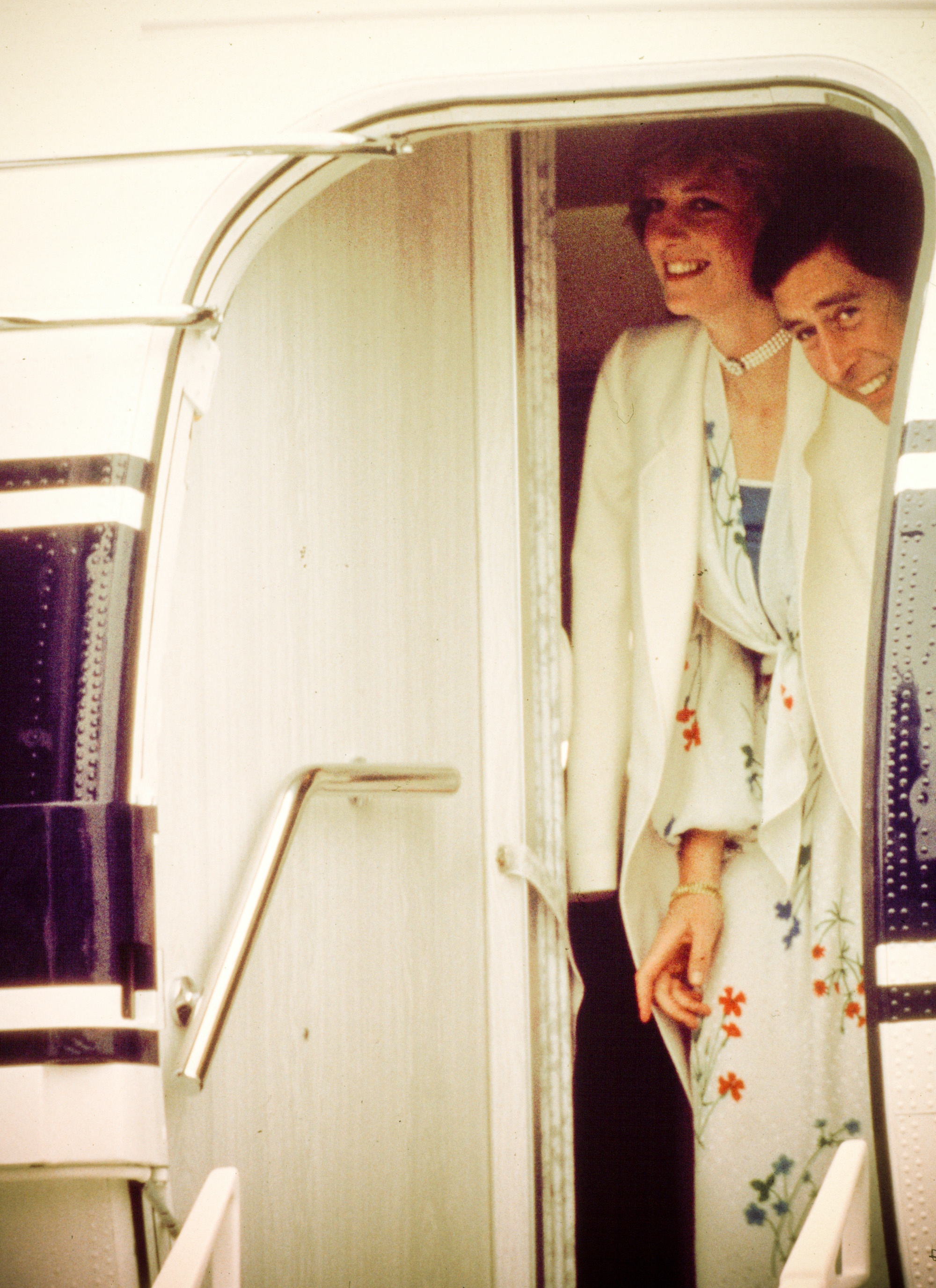 Princess Diana and Prince Charles smile as they board a plane to start their honeymoon