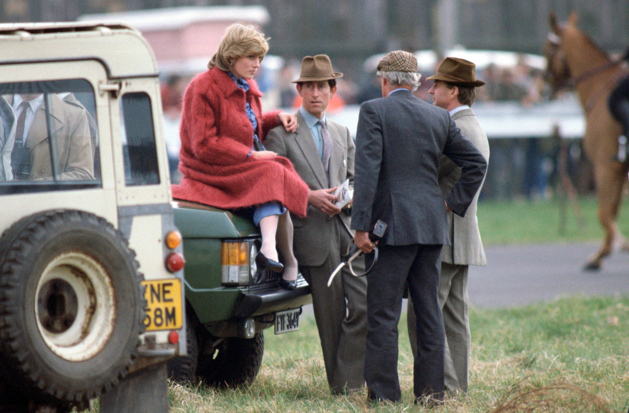 Princess Diana sits on a car at a polo match next to Prince Charles