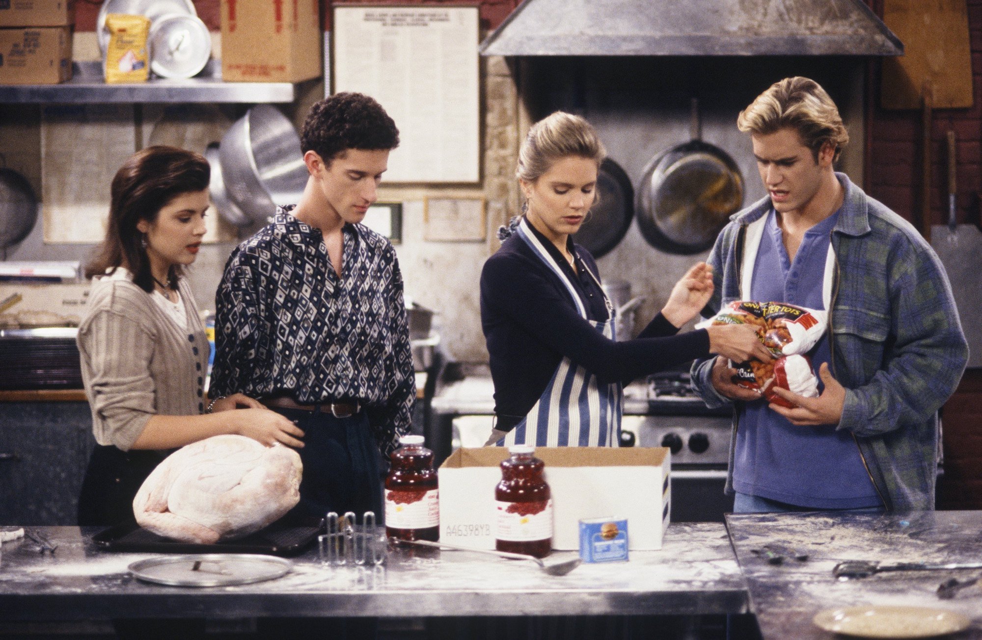 Tiffani Thiessen as Kelly Kapowski, Dustin Diamond as Screech Powers, Anne Tremko as Leslie Burke, Mark-Paul Gosselaar as Zack Morris around a kitchen counter