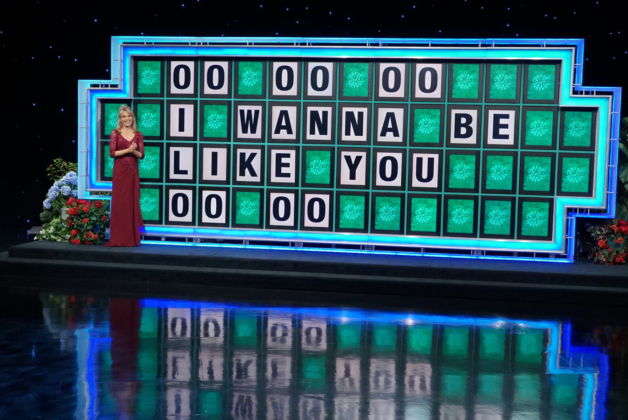 Vanna White smiling next to the Wheel of Fortune letterboard