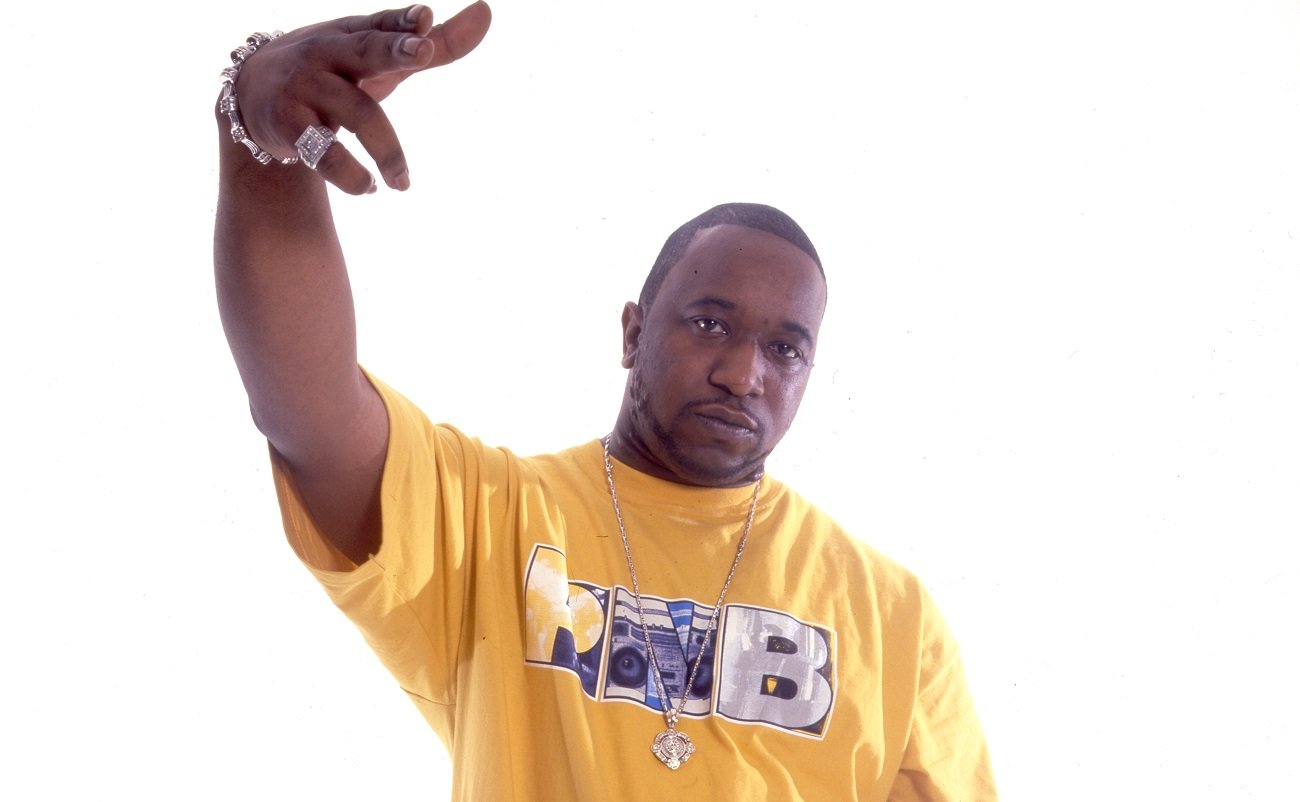 Kool G Rap portrait with his arm raised, yellow T shirt